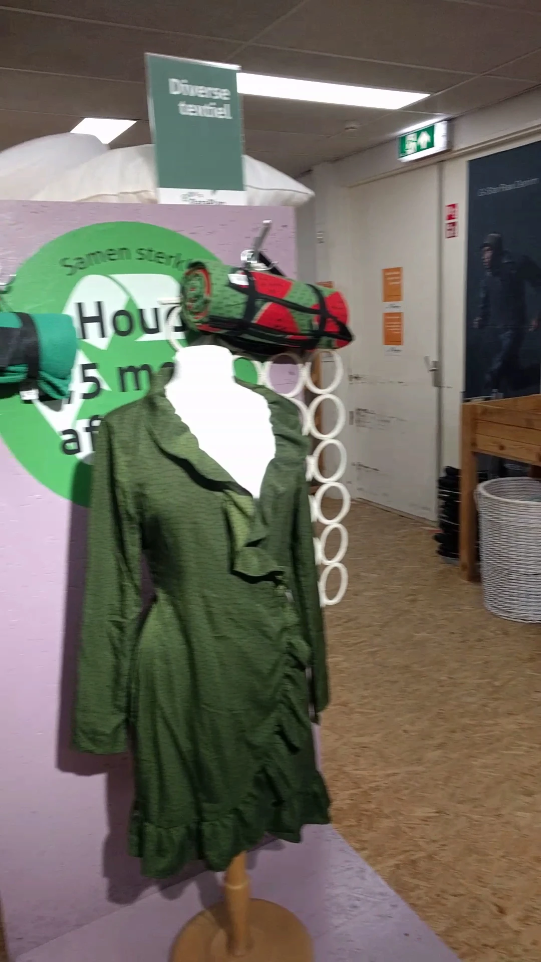 Groene kleding op hangers in de winkel, gedeeltelijk zichtbaar