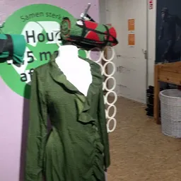 Groene kleding op hangers in de winkel, gedeeltelijk zichtbaar