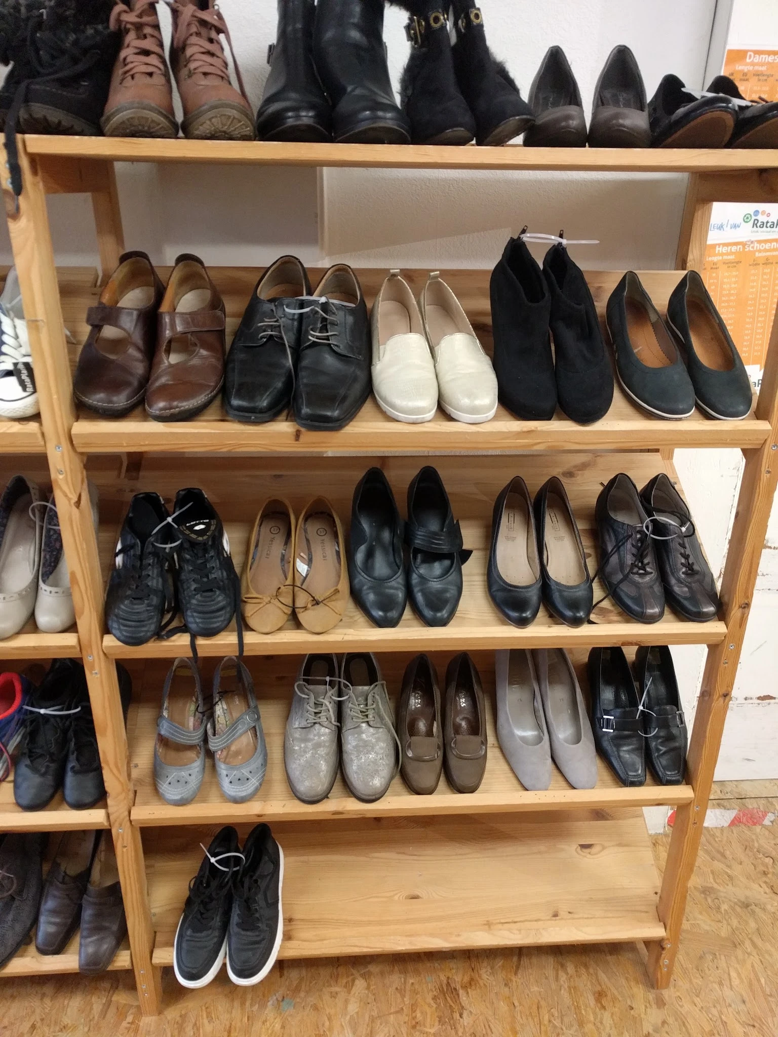 Houten stellingen vol met tweedehands schoenen en laarzen in verschillende kleuren en stijlen