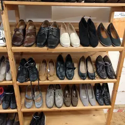 Houten stellingen vol met tweedehands schoenen en laarzen in verschillende kleuren en stijlen