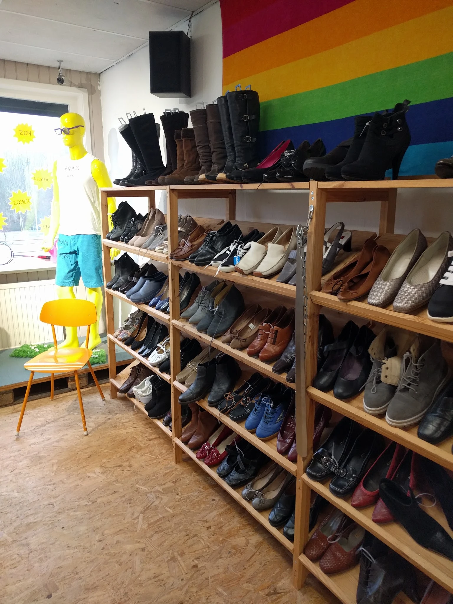 Houten stellingen vol met schoenen en laarzen in verschillende kleuren en stijlen
