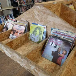 Drie houten bakken met tweedehands dvd's en blu-rays uitgestald in de winkel