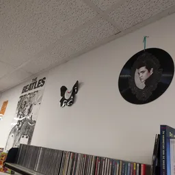 Witmuur met The Beatles-poster, vinyl record artwork en CD-collectie op plank