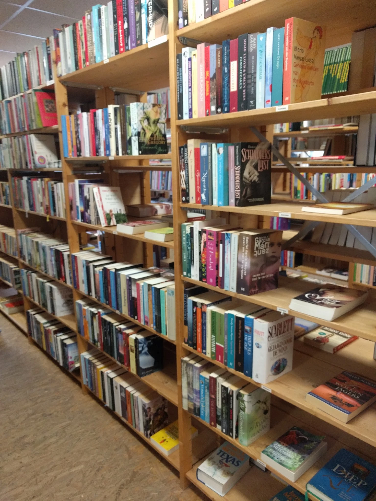 Houten boekenkasten gevuld met tweedehands boeken in verschillende genres en kleuren