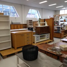Kringloopwinkel met uitgestalde meubels: houten kasten, tv-meubel, boekenkast en zwarte stoel