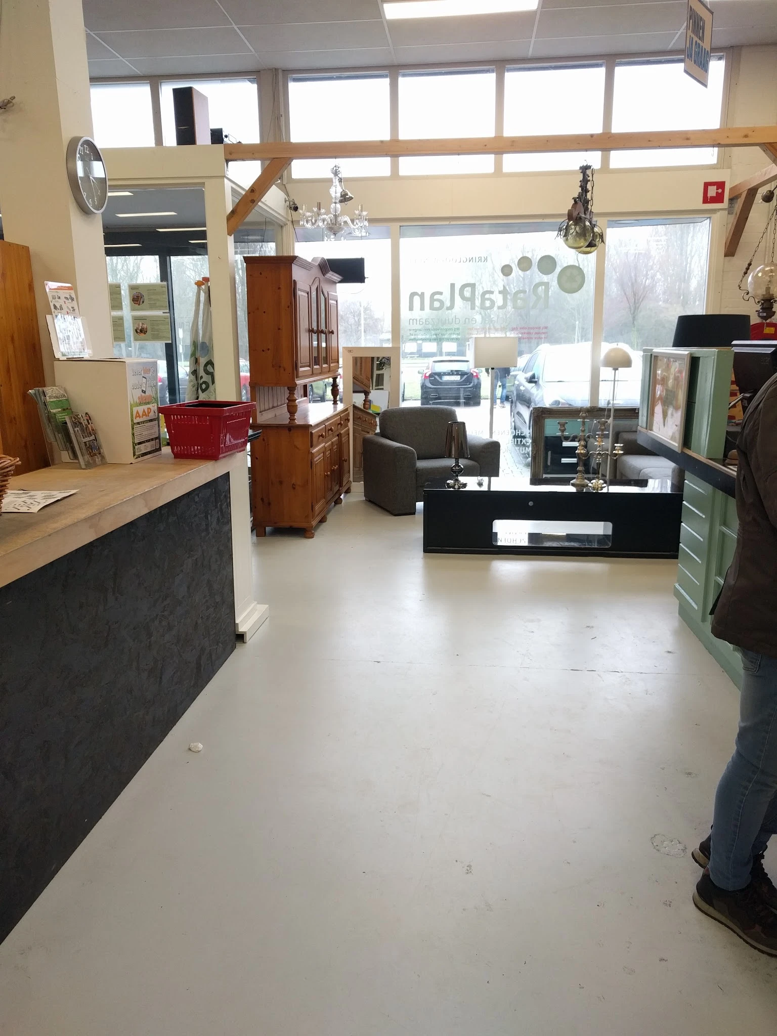 Winkelvloer van kringloopwinkel met stellingen, meubels en toonbanken, zicht op ingang met ramen