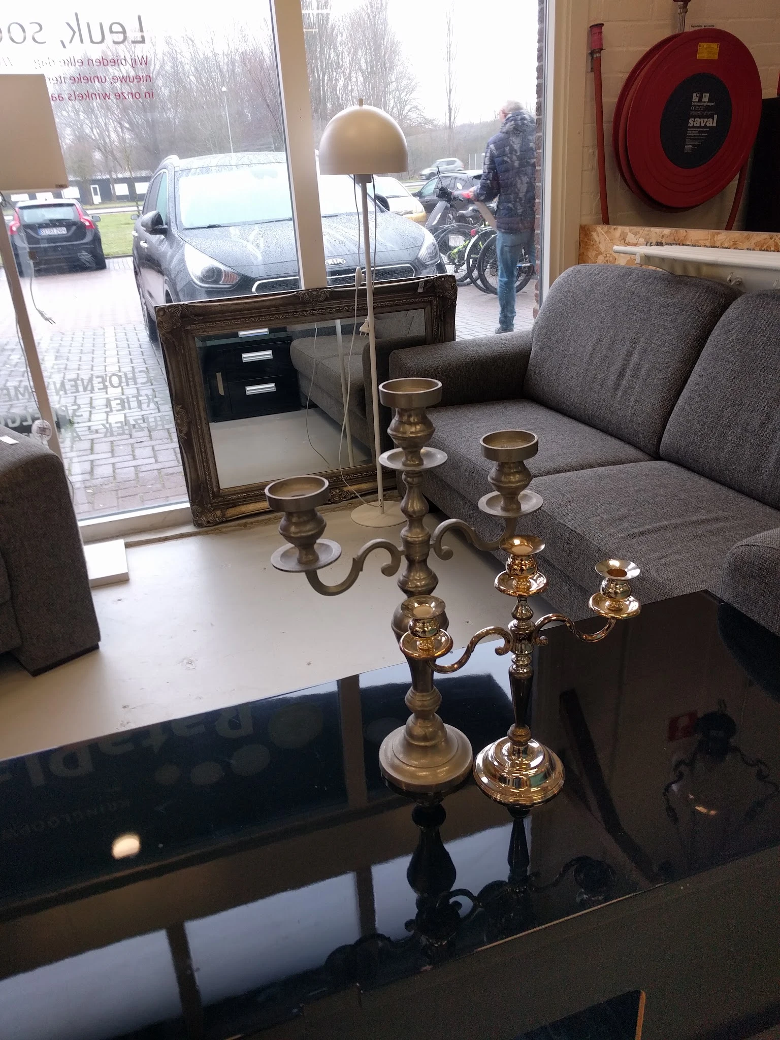 Twee gouden kandelaars met meerdere armen op een witte tafel in de winkel