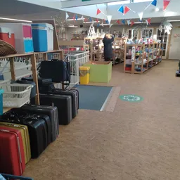 Winkelvloer met koffers, stellingen met spullen en verschillende afdelingen in de kringloopwinkel