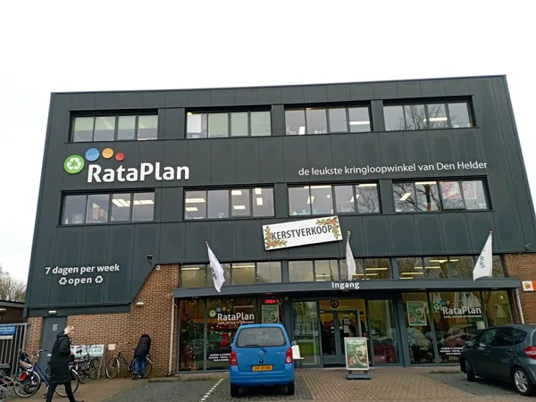 Gevel van kringloopwinkel RataPlan met grote ramen, groene gevelbekleding en duidelijk zichtbaar logo en winkelnaam