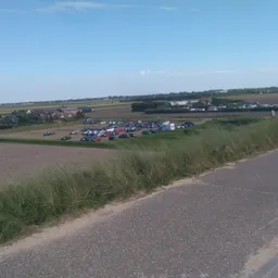 Landelijk landschap met velden, wegen en enkele gebouwen in de verte