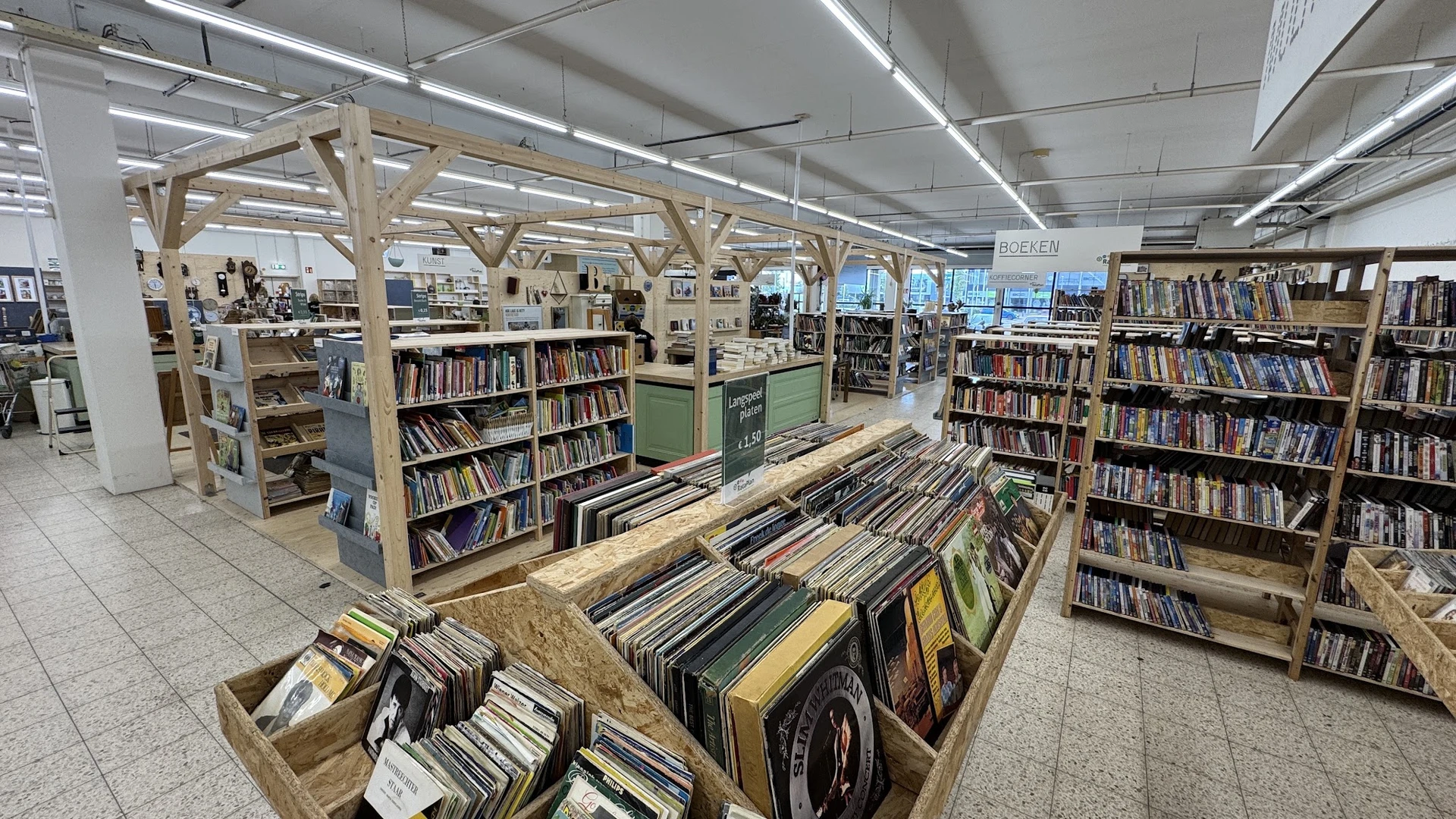 Winkelinterieur met houten stellingen en rekken vol boeken, cd's en vinyl in een kringloopwinkel