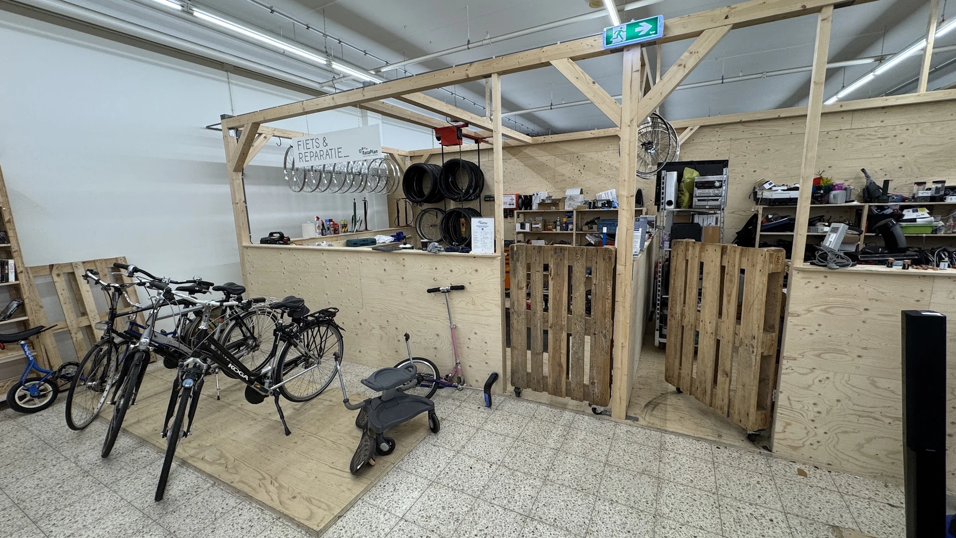 Winkelinterieur met houten constructie, fietsen, elektrische steps en stellingen met diverse spullen