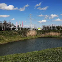 Industrieel terrein met water en groen, uitzicht op fabrieksgebouwen en masten