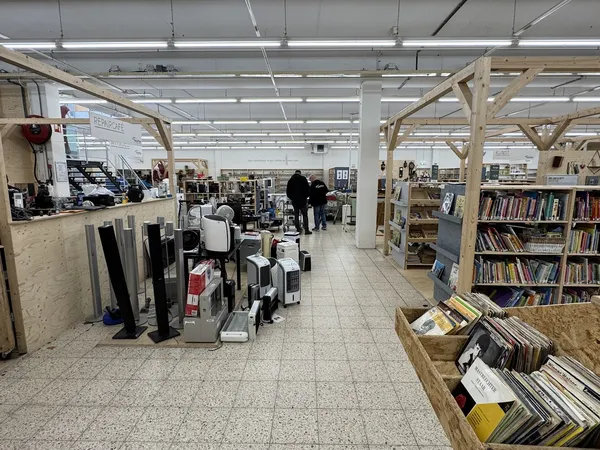 Winkelvloer van kringloopwinkel met boeken, vinylplaten, huishoudartikelen en meubels op houten stellingen