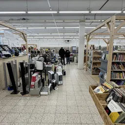 Winkelvloer van kringloopwinkel met boeken, vinylplaten, huishoudartikelen en meubels op houten stellingen
