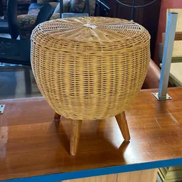 Rieten poef of bijzettafel met houten poten op houten tafel