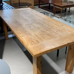 Houten eettafel met natuurlijke houtnerf en patina, gezien vanaf de zijkant in de winkel