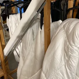 Witte gewatteerde jassen en jacks opgehangen aan een rek in de winkel