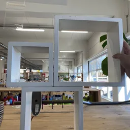 Twee grote witte kasten met glazen deuren in een kringloopwinkel, met stellingen en spullen zichtbaar