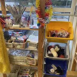 Stellingen en bakken met diverse tweedehands spullen, decoraties en textiel in een kringloopwinkel