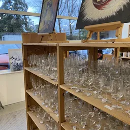 Houten stellingen vol met glaswerk en drinkglazen in verschillende vormen en maten