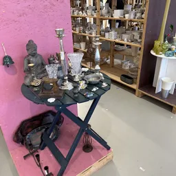 Decoratieve items en huisraad op een zwarte tafel tegen roze muur