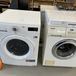 Twee witte en beige wasmachines naast elkaar, uitgestald in de kringloopwinkel