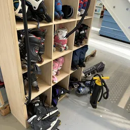 Houten stellingkast met diverse tweedehands spullen: rolschaatsen, skateboard, helm en ander sportmateriaal