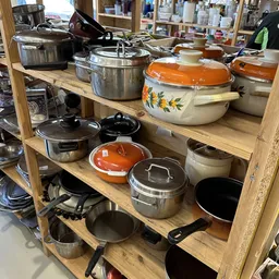 Houten stellingkast met diverse gebruikte pannen, potjes en kookgerei in verschillende kleuren en stijlen