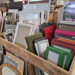 Houten kist met diverse fotolijsten in verschillende kleuren en maten, waaronder wit, groen, rood en roze.