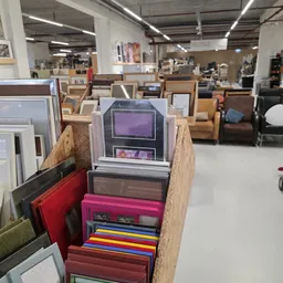 Verzameling vintage elektronische apparaten en andere tweedehands spullen op houten stellingen in de winkel