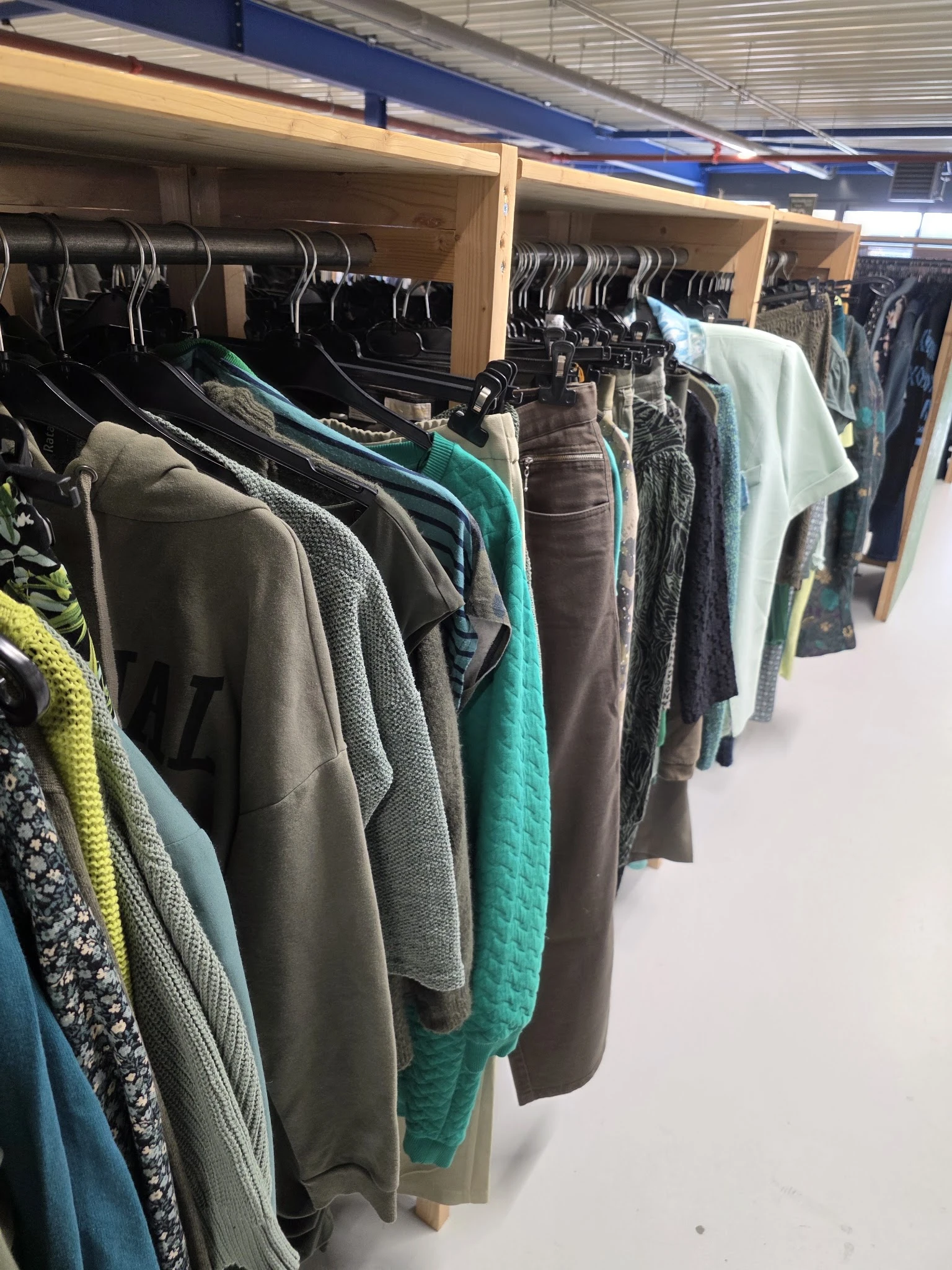 Rekken met tweedehands kleding in verschillende kleuren en stijlen, goed georganiseerd op hangers