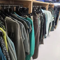 Rekken met tweedehands kleding in verschillende kleuren en stijlen, goed georganiseerd op hangers