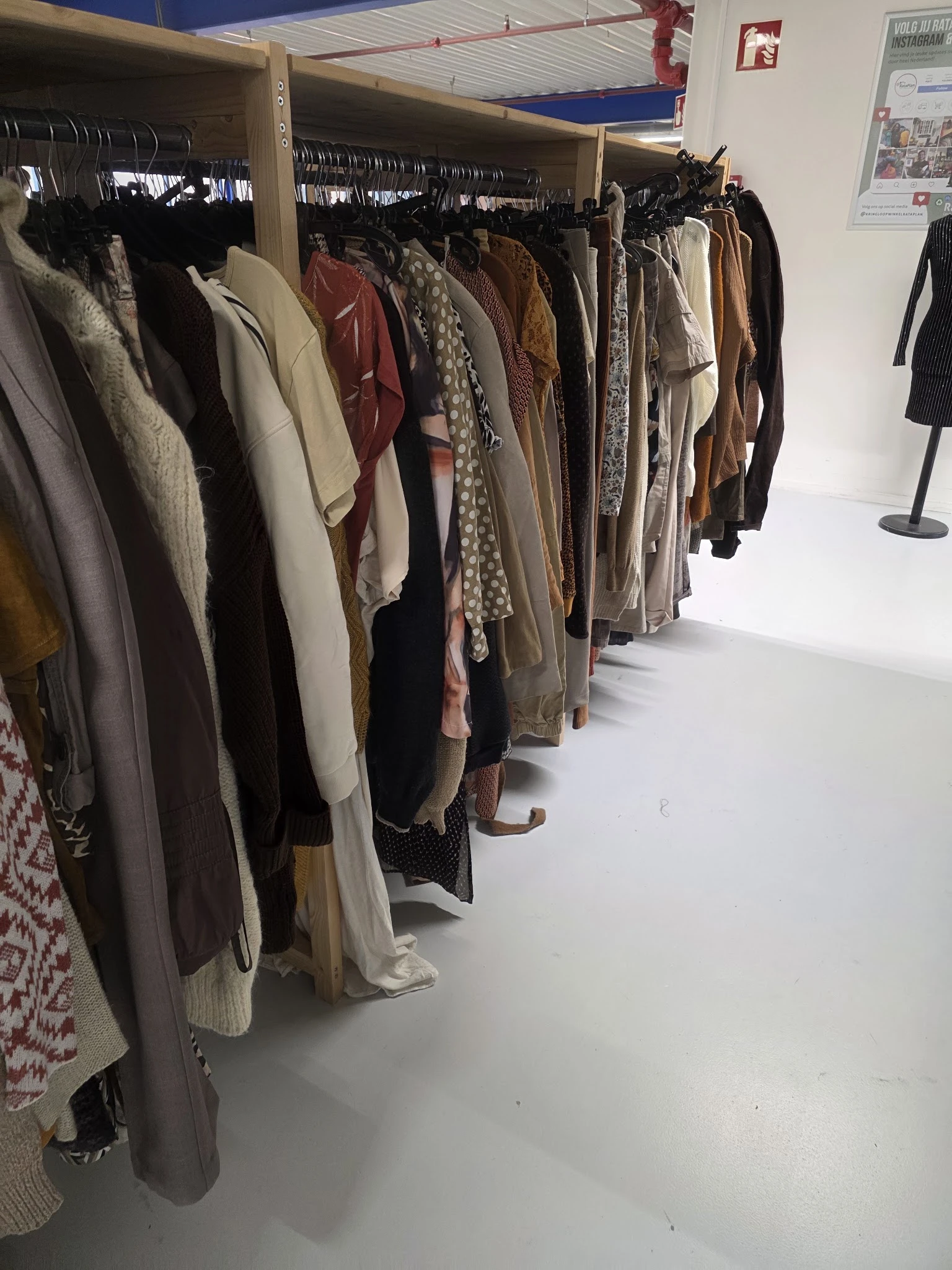 Rekken met tweedehands kleding in verschillende kleuren en stoffen