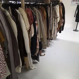 Rekken met tweedehands kleding in verschillende kleuren en stoffen