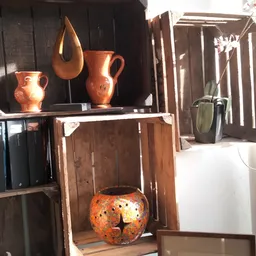 Uitgestalde vintage koperen kannen en keramische potten op houten kastjes en planken
