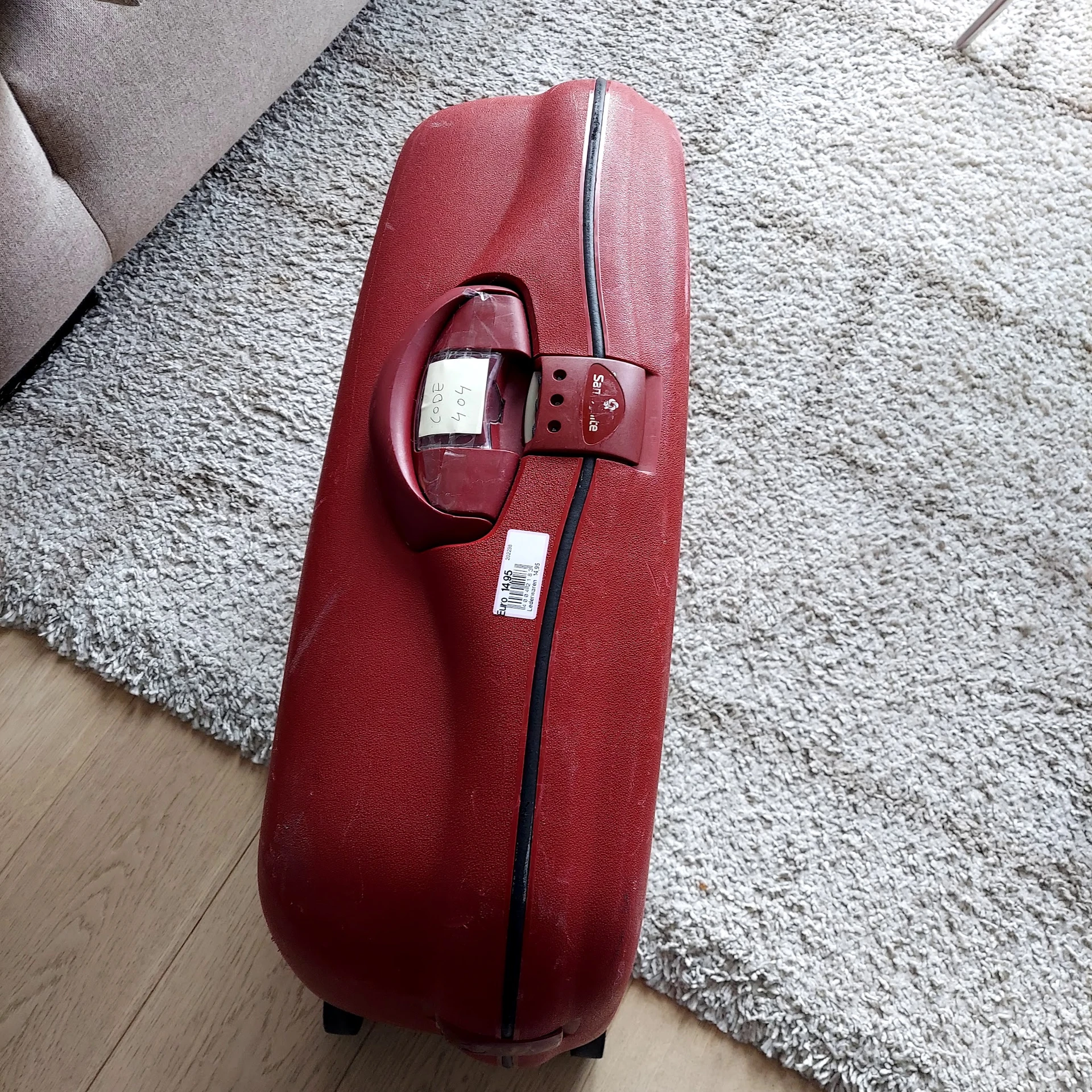 Rood koffertje op grijs tapijt met bagagelabels