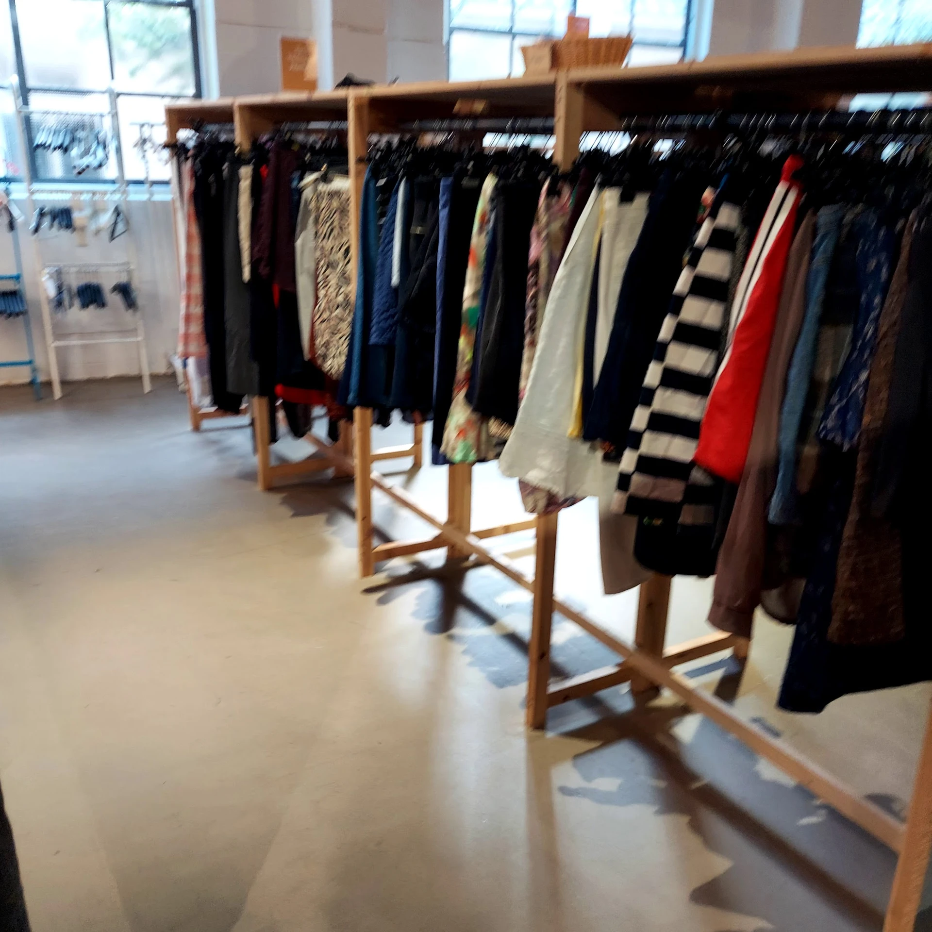 Rekken met tweedehands kleding in verschillende kleuren en stijlen