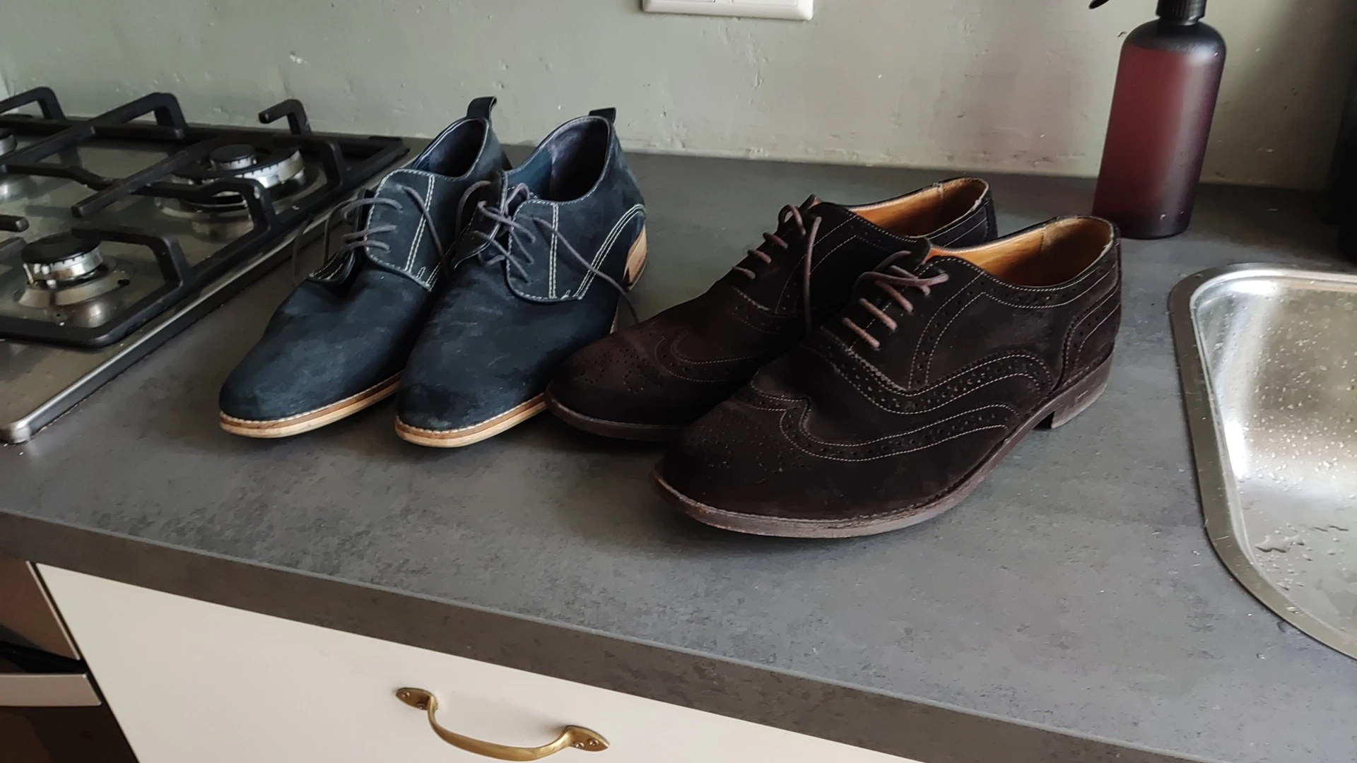 Vier paar herenschoenen in verschillende kleuren en stijlen op een grijze plank uitgestald