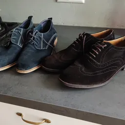 Vier paar herenschoenen in verschillende kleuren en stijlen op een grijze plank uitgestald