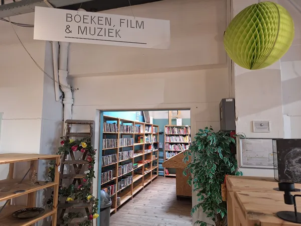 Boekenrek met boeken, film en muziek in de kringloopwinkel met groene decoratieve bol