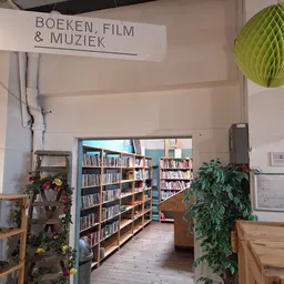 Boekenrek met boeken, film en muziek in de kringloopwinkel met groene decoratieve bol