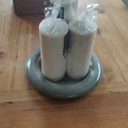 Twee witte flessen in plastic verpakking in een grijze ronde houder op houten vloer