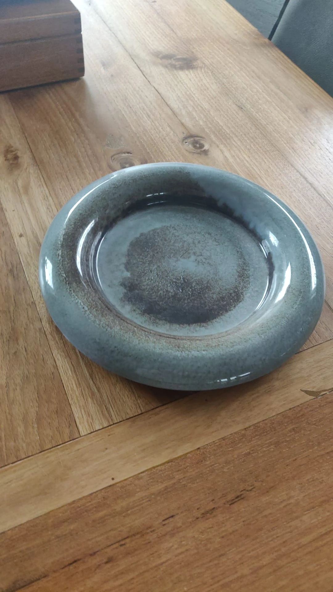 Grijsblauwe glazen schaal met ronde vorm, gezien van bovenaf op houten ondergrond