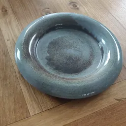 Grijsblauwe glazen schaal met ronde vorm, gezien van bovenaf op houten ondergrond