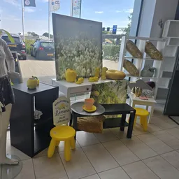 Winkelinterieur met gele decoratieve items, waaronder stoelen en tafels, met een achtergrondposter van citroenen