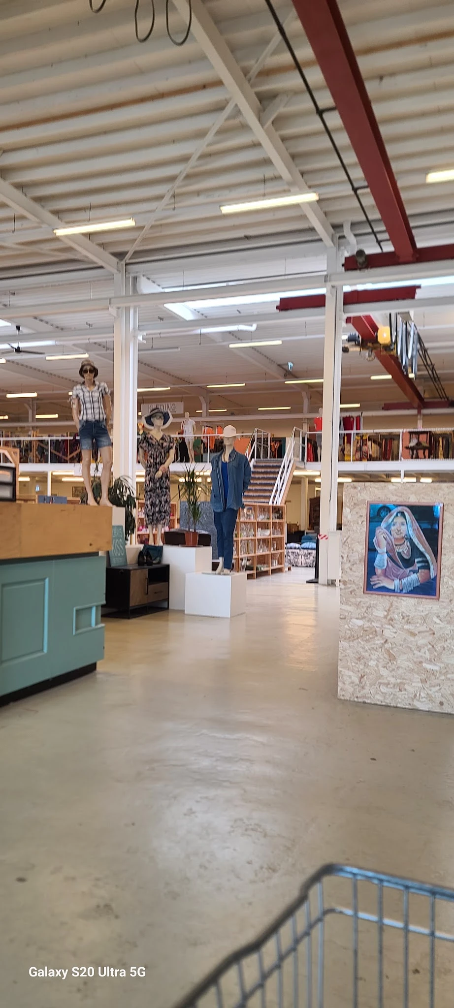 Winkelinterieur met kledingrekken, mannequins in verschillende outfits en diverse artikelen op displays