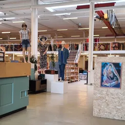Winkelinterieur met kledingrekken, mannequins in verschillende outfits en diverse artikelen op displays