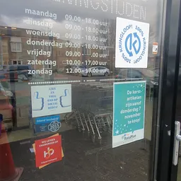 Winkelruit met openingstijden, logo's en promotieborden voor kringloopwinkel