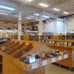 Winkelvloer met houten boekenkasten en uitgestalde boeken in vakken, modern winkelinterieur met kolommen en verlichting